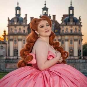 Fotografie einer Frau in einem rosafarbenen Kleid vor einem Schloss